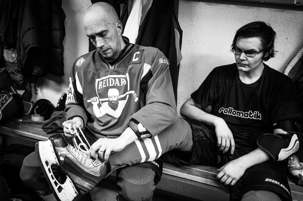 Kapteeni Jari Mikkola avaa olkapää sijoiltaan mököttävän Aleksi Brunnin luistimet. Kuva: Jussi Leinonen